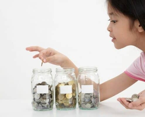 young Asian girl counting coins in three jars