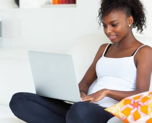 teenage girl with laptop in lap, on couch, using apps that pay teens