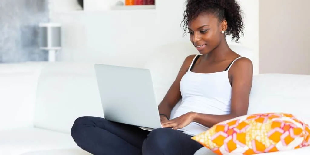 teenage girl with laptop in lap, on couch, using apps that pay teens