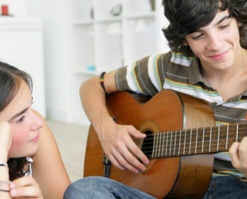 teenage couple on at home date night, teen boy playing his guitar