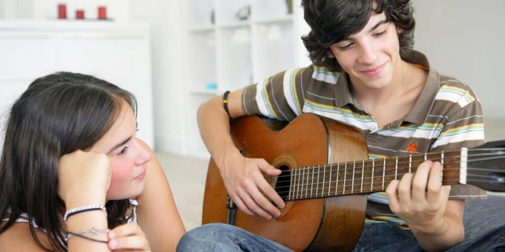 teenage couple on at home date night, teen boy playing his guitar