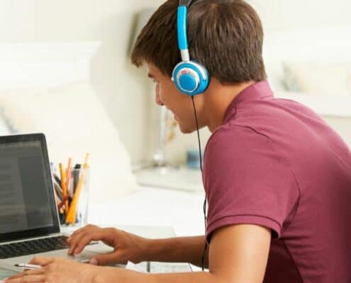 teenage boy on laptop with earphones, doing productive activities for teenagers