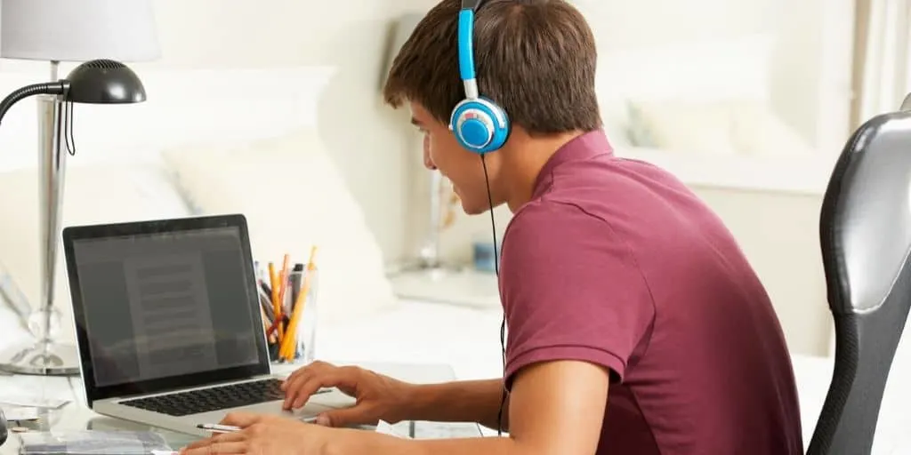 teenage boy on laptop with earphones, doing productive activities for teenagers