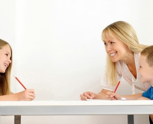mother helping teach kids about investing at table, boy and girl