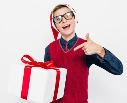 teen boy with glasses and Santa Hat, holding gift - stocking stuffers for teen boys