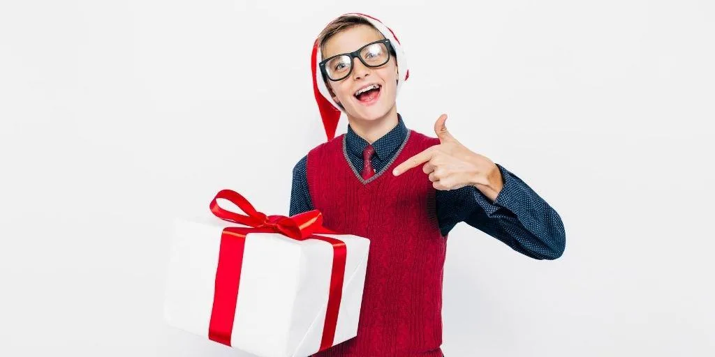 teen boy with glasses and Santa Hat, holding gift - stocking stuffers for teen boys