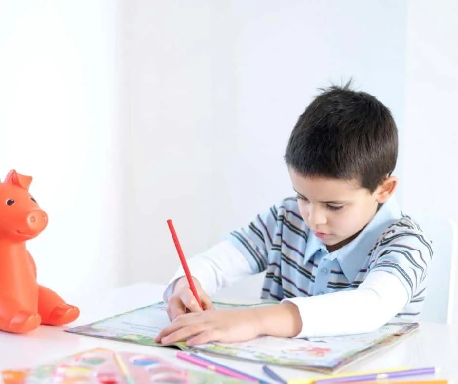 young boy with piggy bank, working on free fun money game for 2nd graders