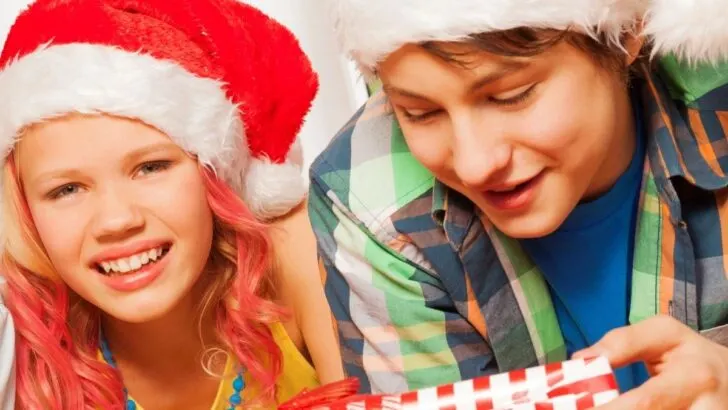 tween boy in Santa hat having fun, opening up gift