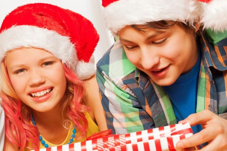 tween boy in Santa hat having fun, opening up gift