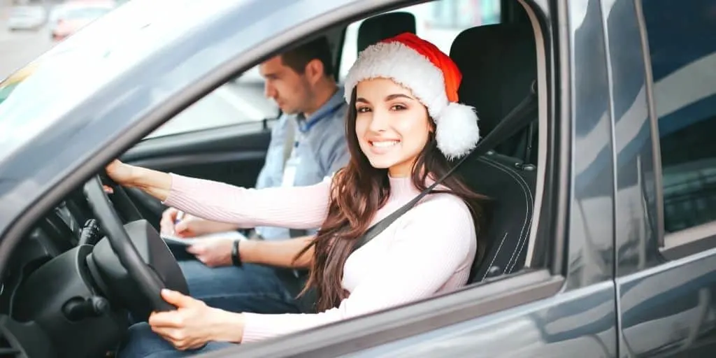 teen girl driver with Santa hat on, trying out stocking stuffers for teenagers she got Christmas morning