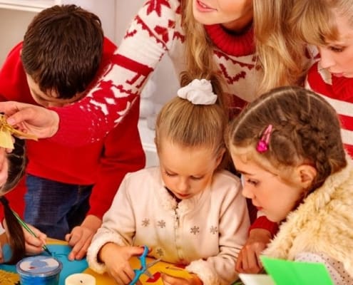 teacher working with students, handing on a stocking stuffer gift - classroom of students