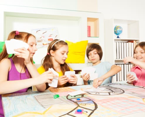 group of kids at a table playing a stock market game for kids to learn investing