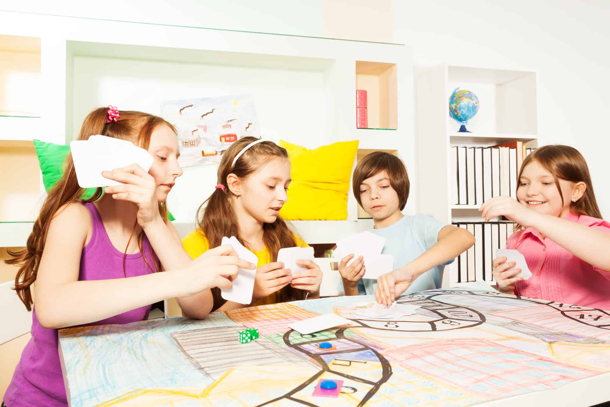 group of kids at a table playing a stock market game for kids to learn investing