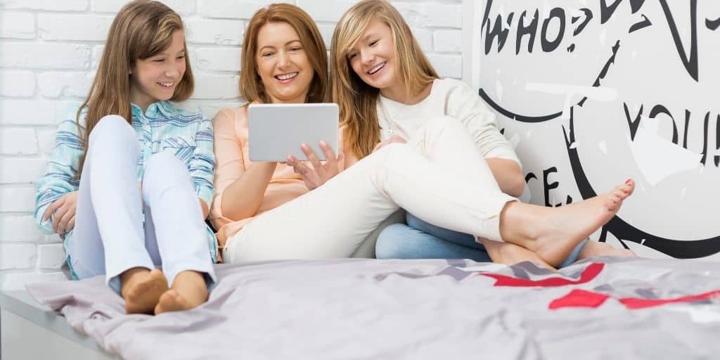 mother with two teen daughters on bed, discussing teen expenses and money responsibilities