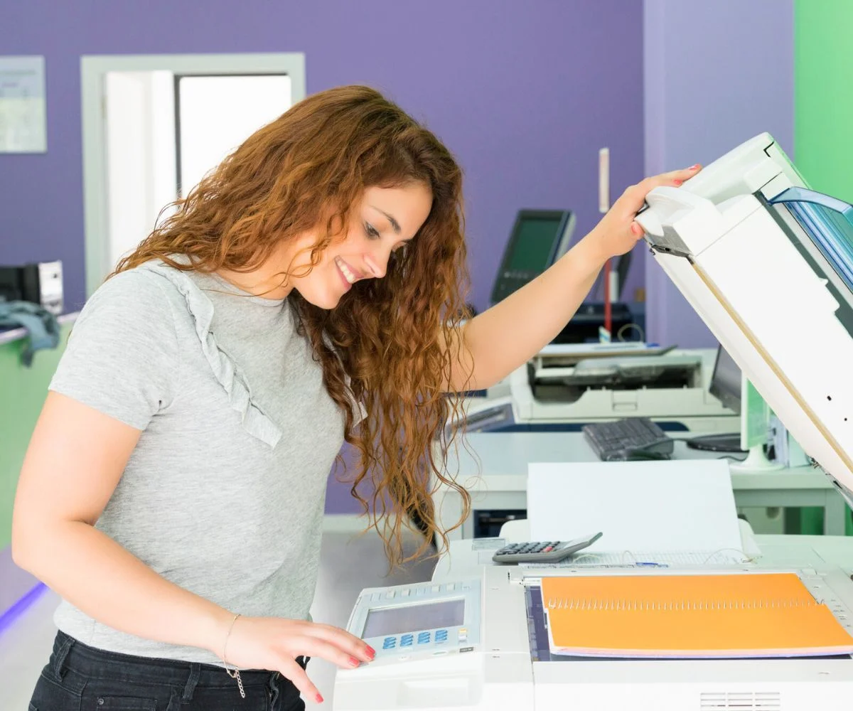teen girl making photo copies and smiling in office