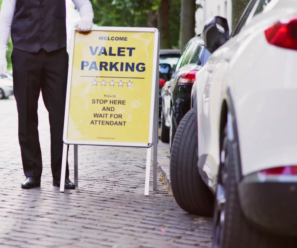 teen dressed in valet uniform at valet sign