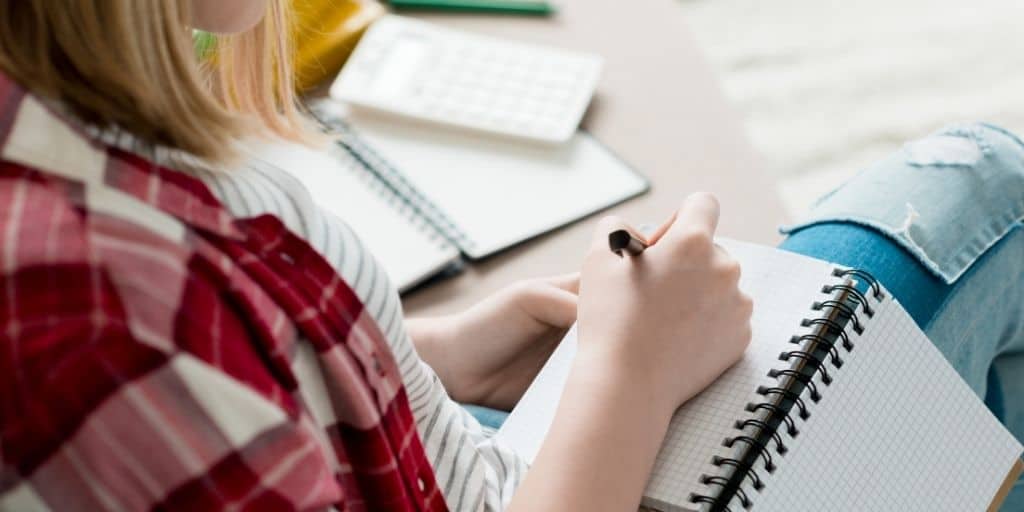 teen girl writing new year resolutions for teens on couch