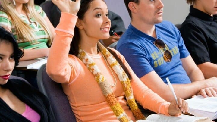row of high school students with girl in orange shirt raising hand