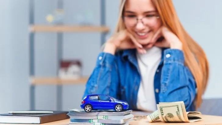 teen girl smiling at car savings pile