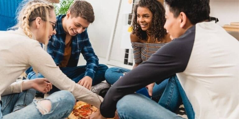group of teens around a pizza, having a good time