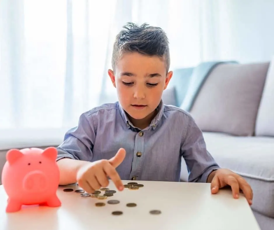 young boy with pink piggy bank, counting out his money