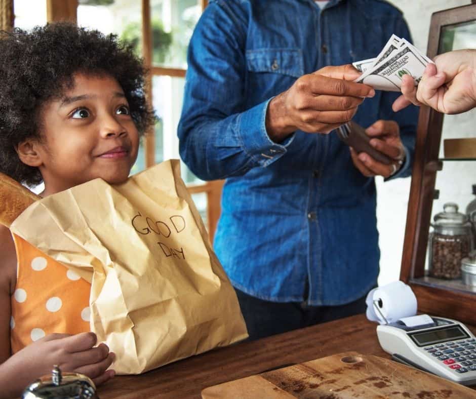 daughter and father at store, father paying for something and daughter looking on the transaction, smiling