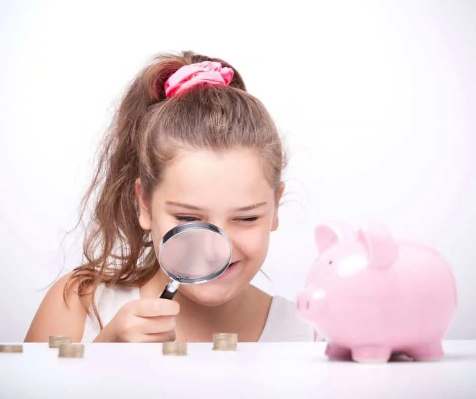 tween girl with magnifying glass looking at piles of coins, next to piggybank, smiling