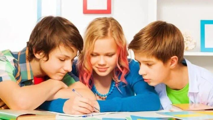 three older kids at desk writing business plan