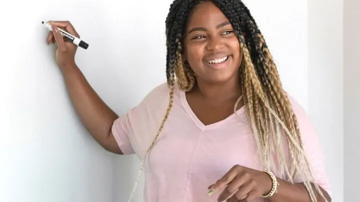 teenager girl in pink shirt smiling, write entrepreneur ideas from toolbox on whiteboard