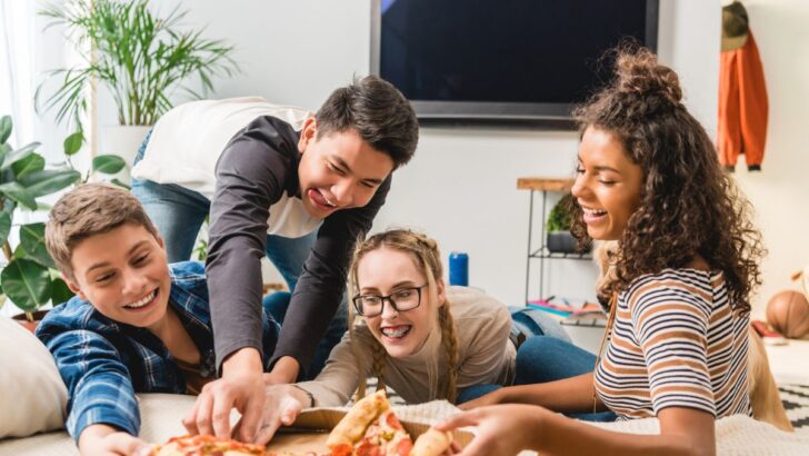 group of teens hanging out grabbing pizza slices