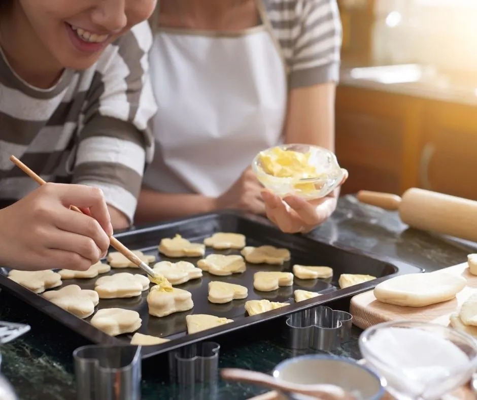 teen working with parent to decorate pan of sugar cookies