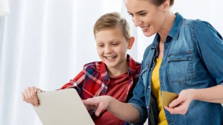 mom with tween son on computer, using goalsetter cashola debit card to make online purchase