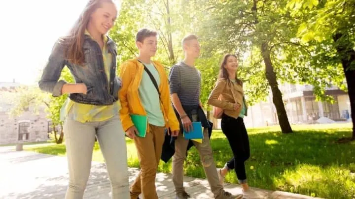 group of high school students in fall walking down walkway with smiles