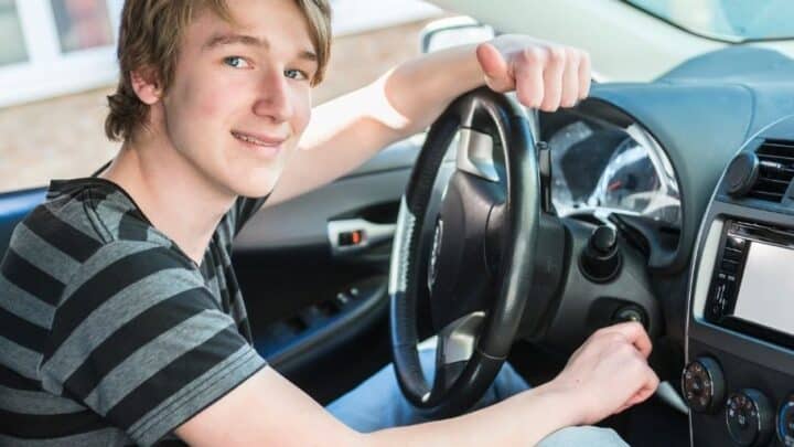 teen boy driver behind wheel, smiling