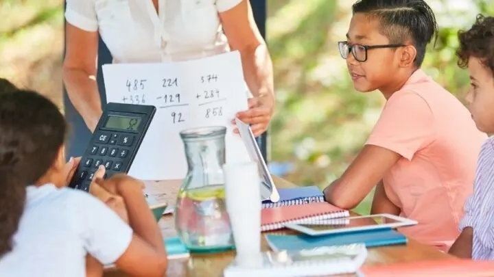 group of tweens with teacher at end of table, calculating lemonade stand math