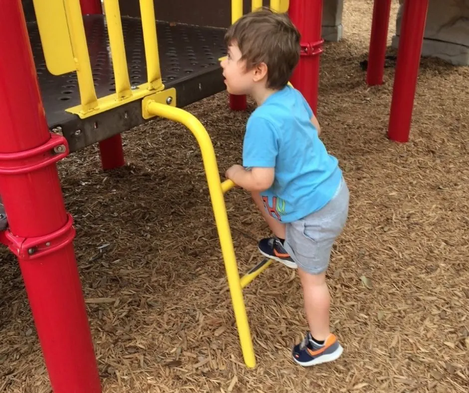 3-year-old climbing up the small ladder on a playground, doing a circuit park activity