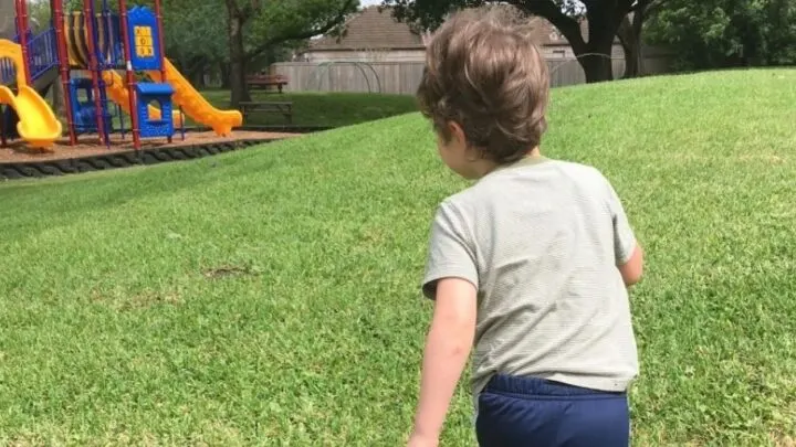 preschooler running towards a playground in a park