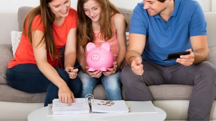 tween with mom and dad and piggybank, tracking their money by paper