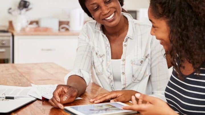 mom with daughter at kitchen table, smiling, teaching teen the value of money