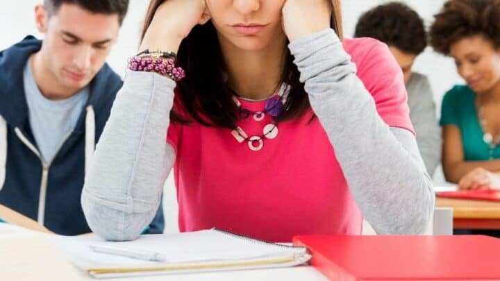 teenage girl with head in hands, thinking about her teenage financial problems