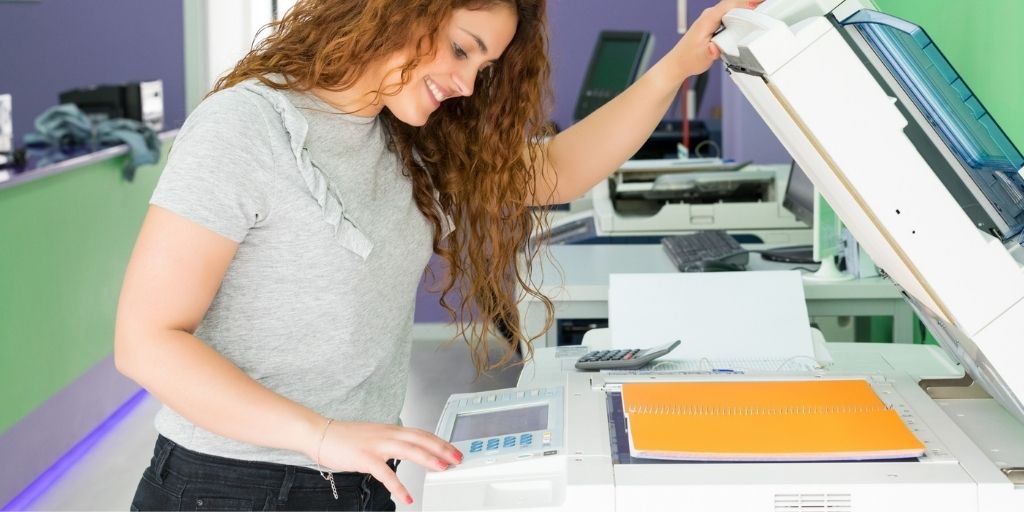 teen girl making photocopies and smiling, at her first teen job