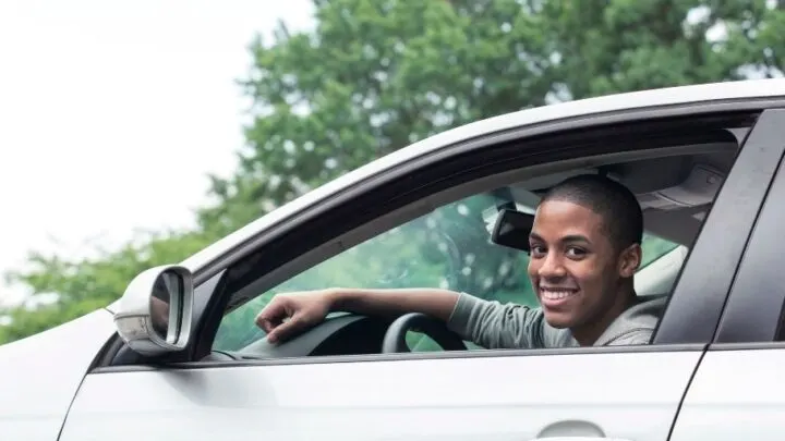 teen boy in driver seat of car, smiling