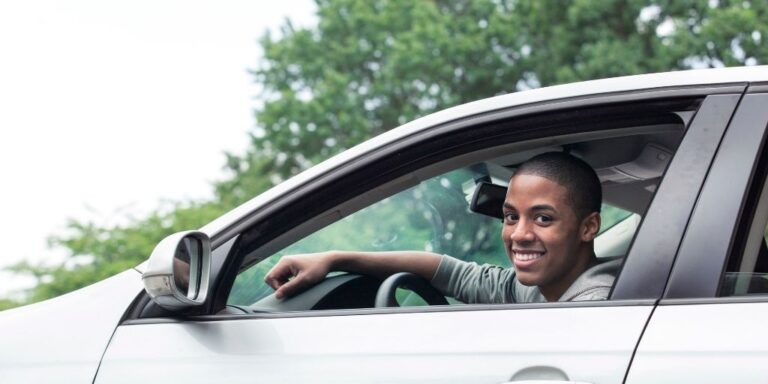 teen boy in driver seat of car, smiling