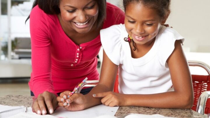 mother in pink shirt helping daughter with practice paying bills worksheets