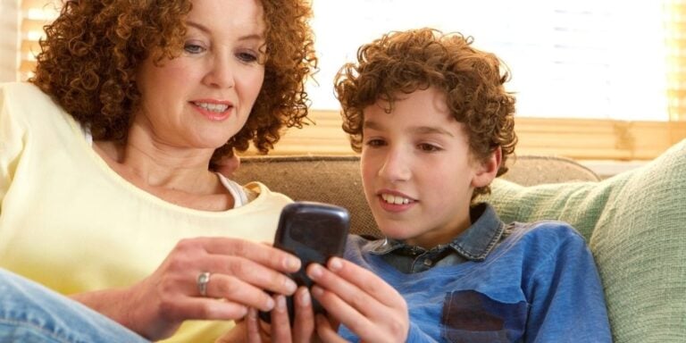 mother and son looking at busykid prepaid debit card app on phone, on couch