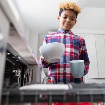 older kid putting dishes into dishwasher as chore to do around the house