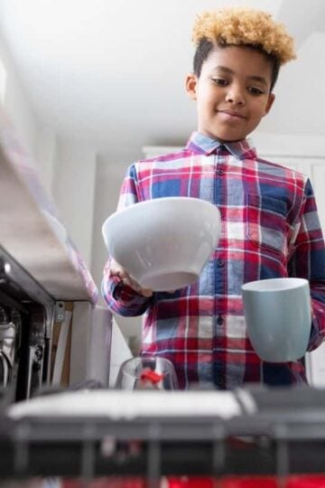 older kid putting dishes into dishwasher as chore to do around the house