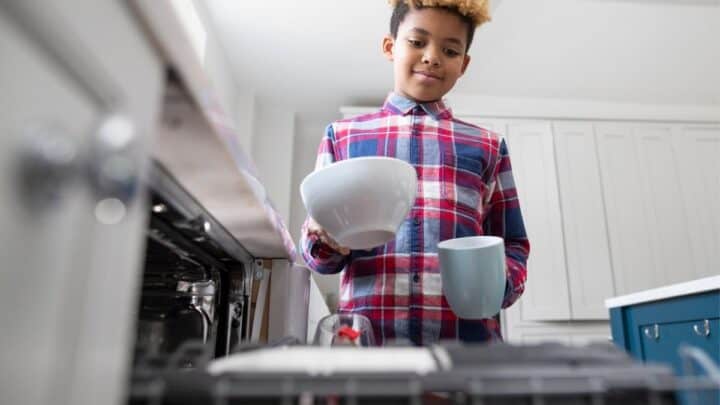 older kid putting dishes into dishwasher as chore to do around the house