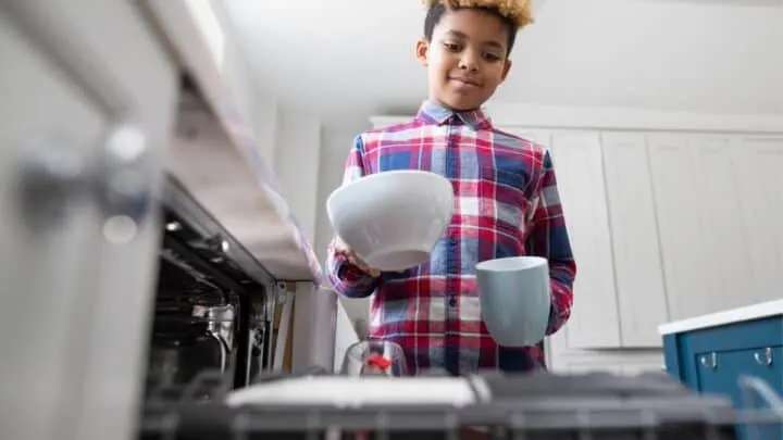older kid putting dishes into dishwasher as chore to do around the house