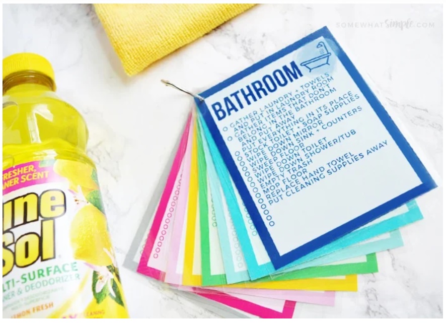 brightly framed chore card checklists by room with bottle of pine sol cleaner on left side